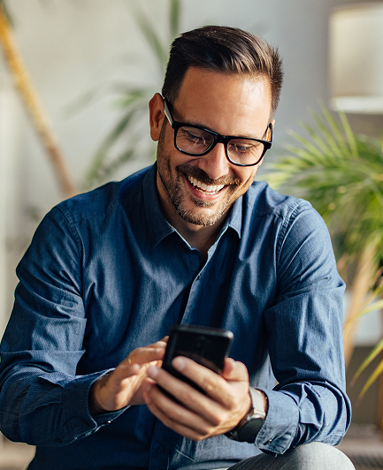 Man wearing glasses and blue shirt, smiling, using his smartphone to book ers demo