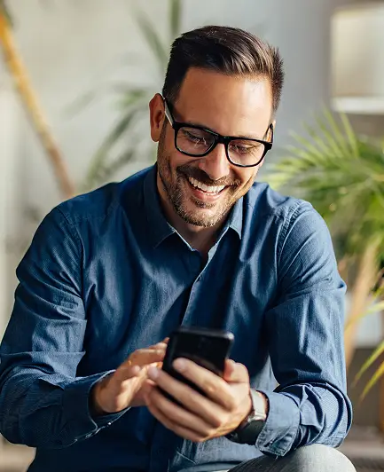 Man wearing glasses and blue shirt, smiling, using his smartphone to book ers demo